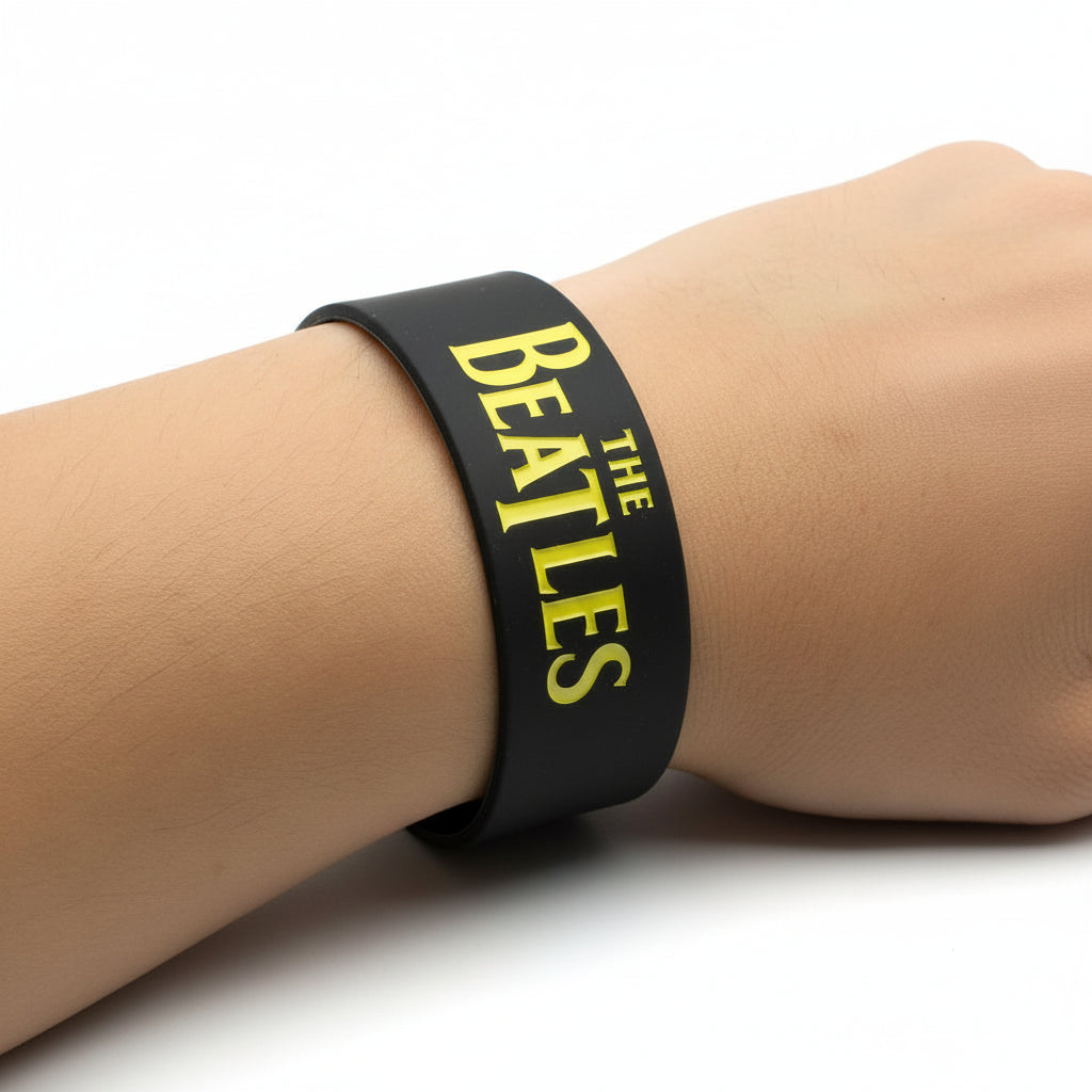 Breites THE BEATLES Silikonarmband aus schwarzem Gummi mit klarem Band‑Logo in 2,5 mm Stärke